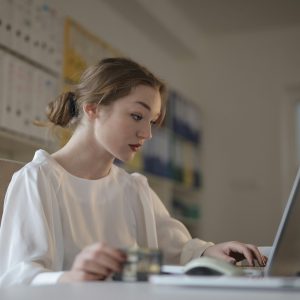 Focused young woman working remotely on a laptop in a modern office.